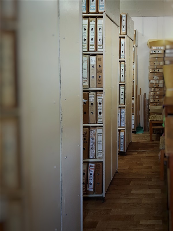 Archival documents stored in a standardised documentation department, showing rows of organised institutional records.