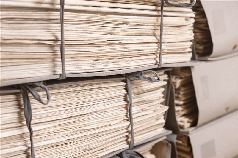 Stacks of archival documentation files and paperwork in an institutional records facility.