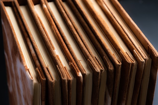 Neatly stacked finished print materials with textured covers in an archival storage setting.